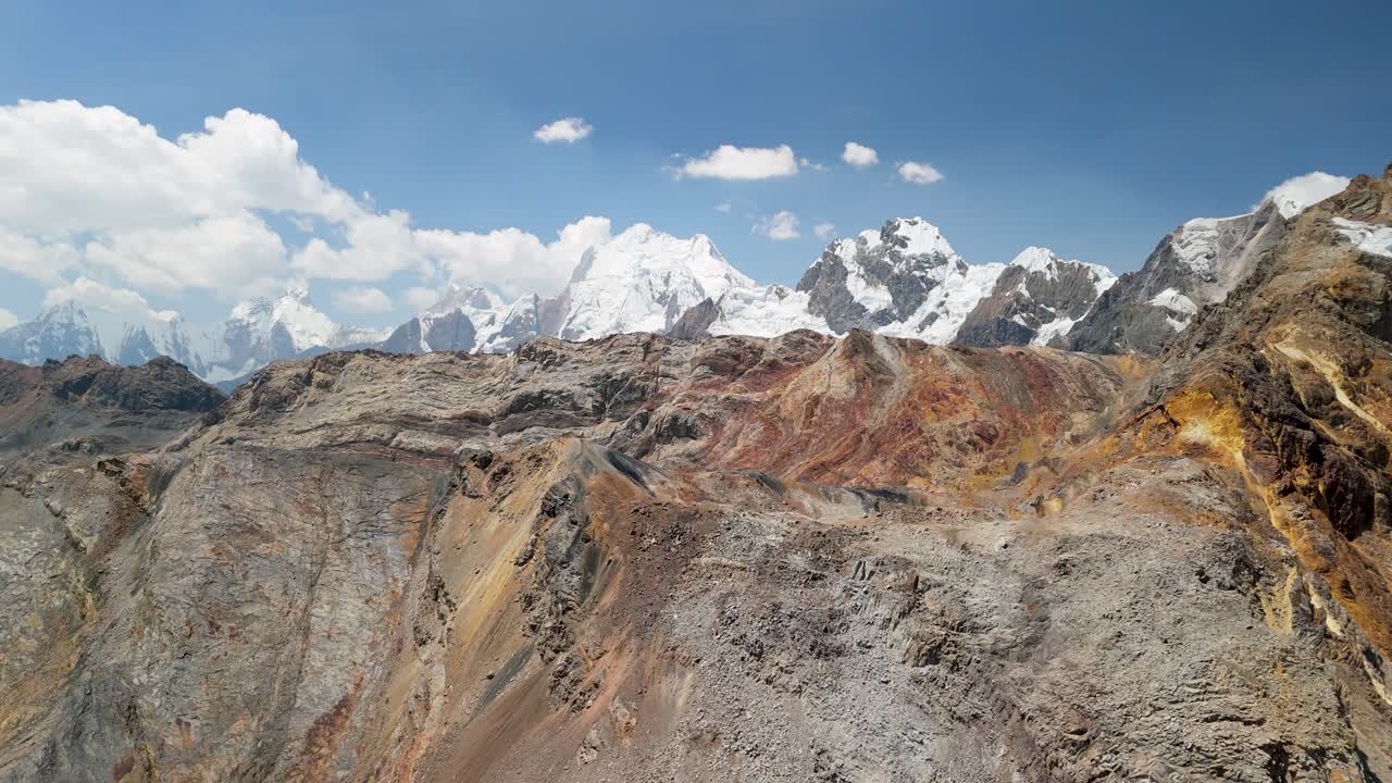 Colorful, mineral-rich mountains of the remote Huayhuash trek, revealing the majestic snow-capped peaks of the Andes in Peru - epic aerial flyover