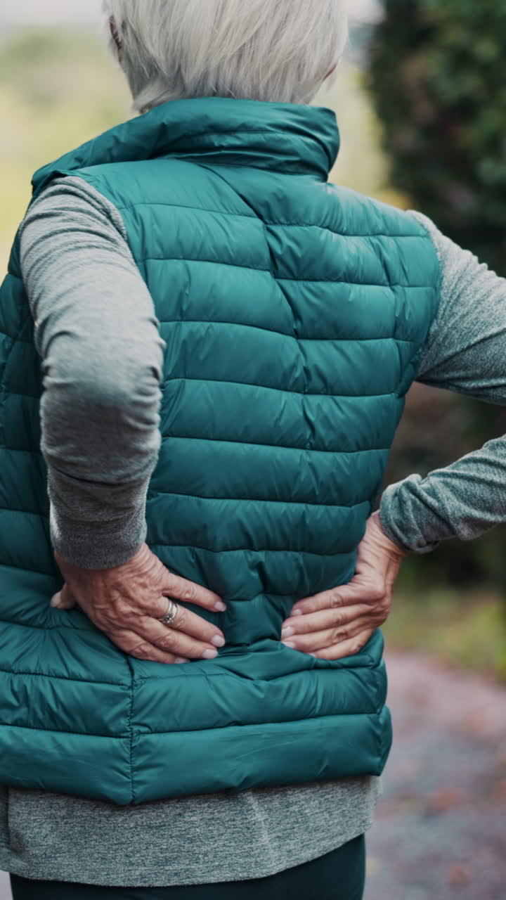 Senior woman experiencing back pain outdoors