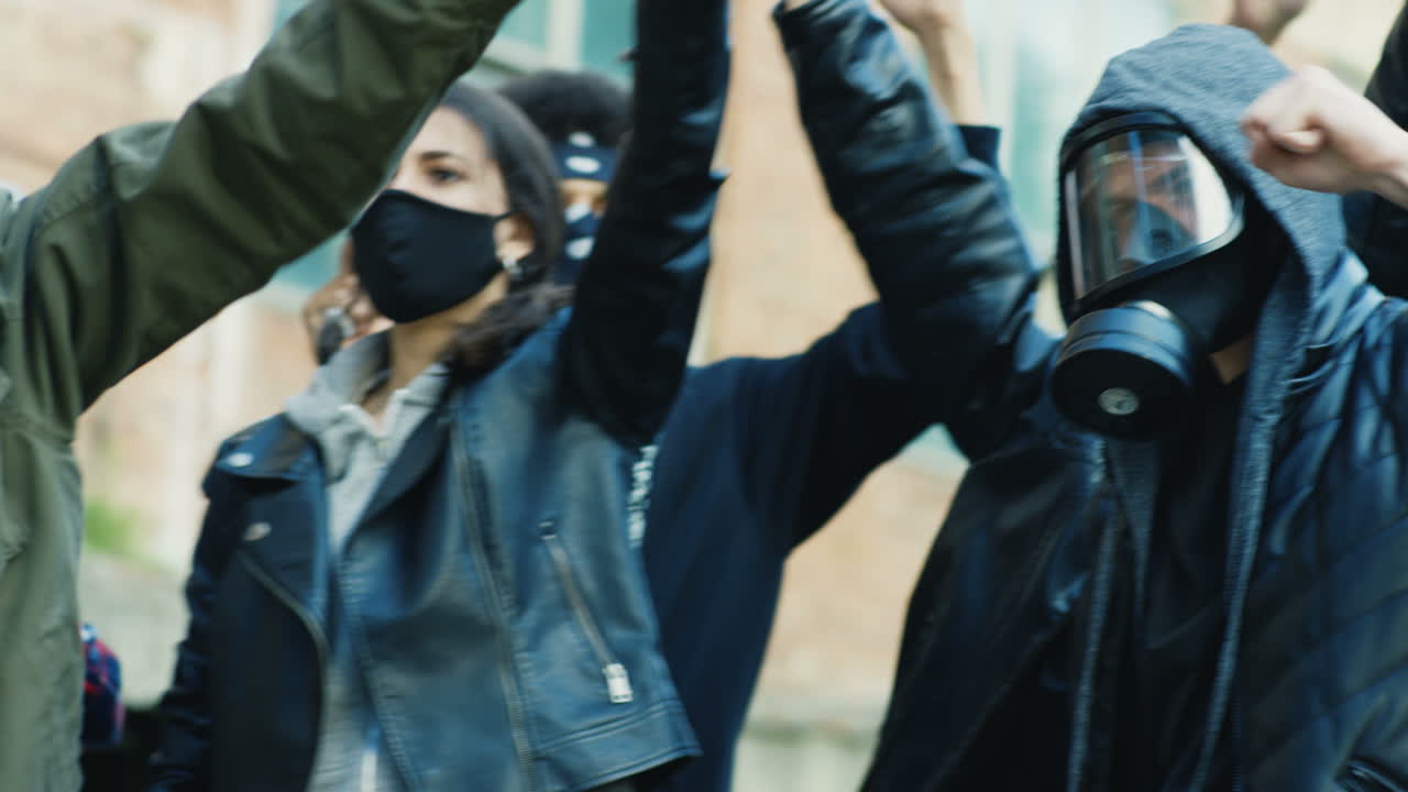 группа мультиэтнических людей кричит с поднятыми руками в знак протеста против расизма на улице