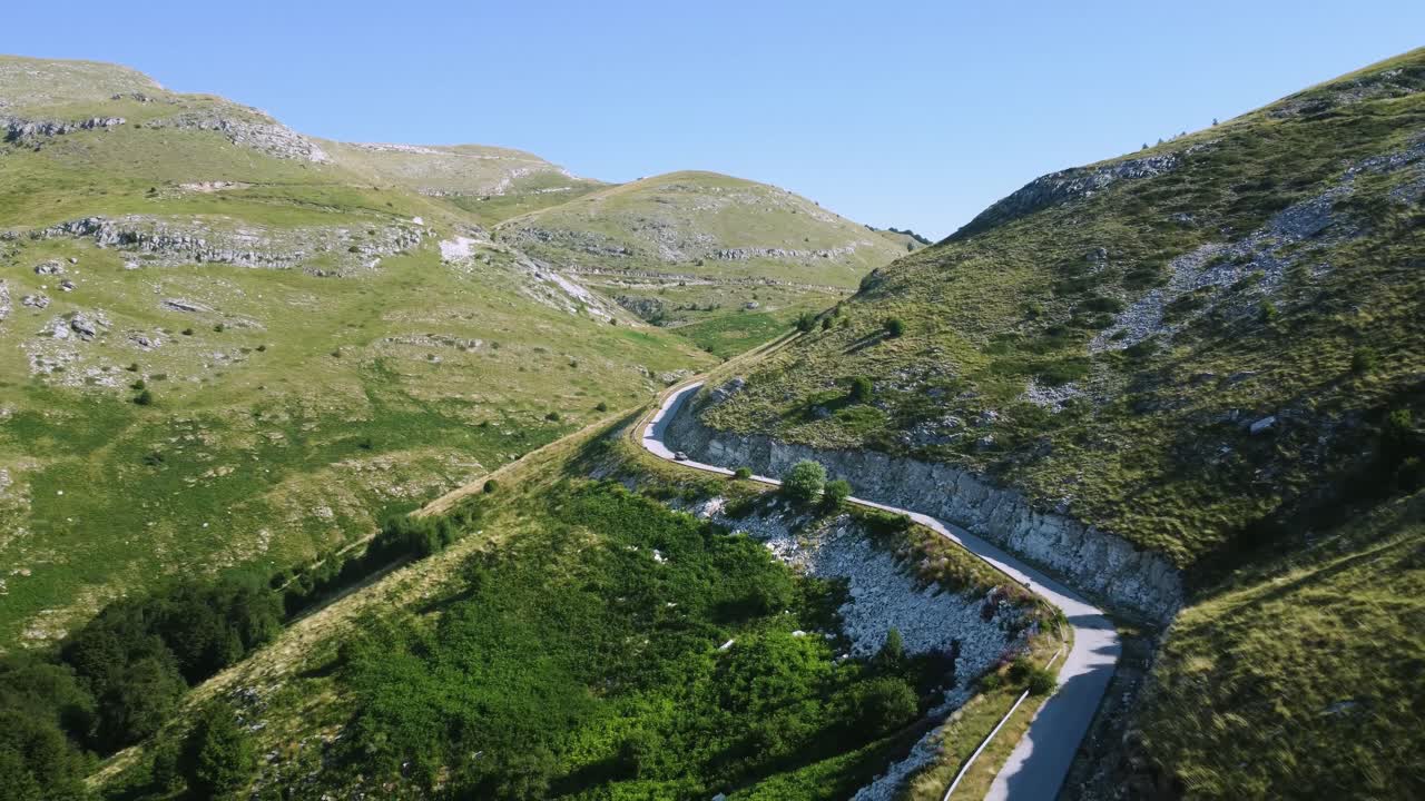 antena de carreteras estrechas de montaña debajo del pico y un coche de jeep viajando a través de ellos