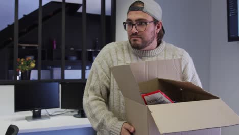 caucasian man carrying cardboard box in creative office