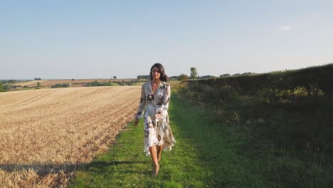 Una-Mujer-Joven-Y-Moderna-Con-Un-Vestido-Floral-Que-Fluye-Camina-Hacia-La-Cámara-Con-Un-Propósito