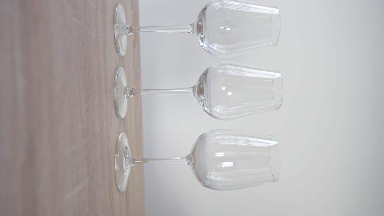 Empty white wine glass between two red wine glasses on wooden table
