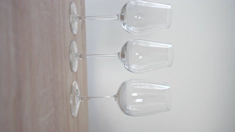 empty white wine glass between two red wine glasses on wooden table