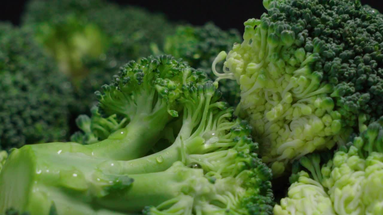 Closeup Tilt Down of Broccoli Pieces with Water Droplets on Black Background