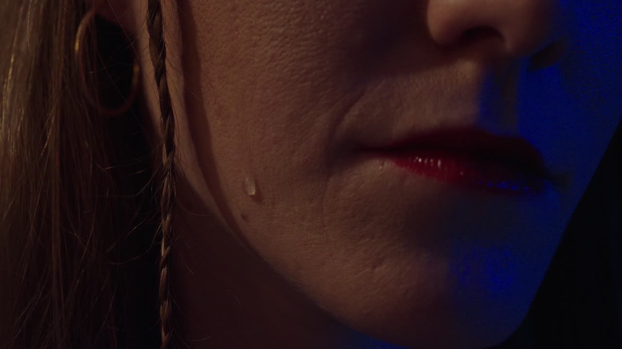Cinematic close-up of a single tear slowly rolling down a woman’s cheek under dramatic light. Ideal for sadness, heartbreak, emotion, pain, or cinematic storytelling themes