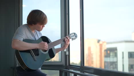 man playing acoustic guitar on balcony