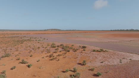 vast arid landscape with red earth and pink lake