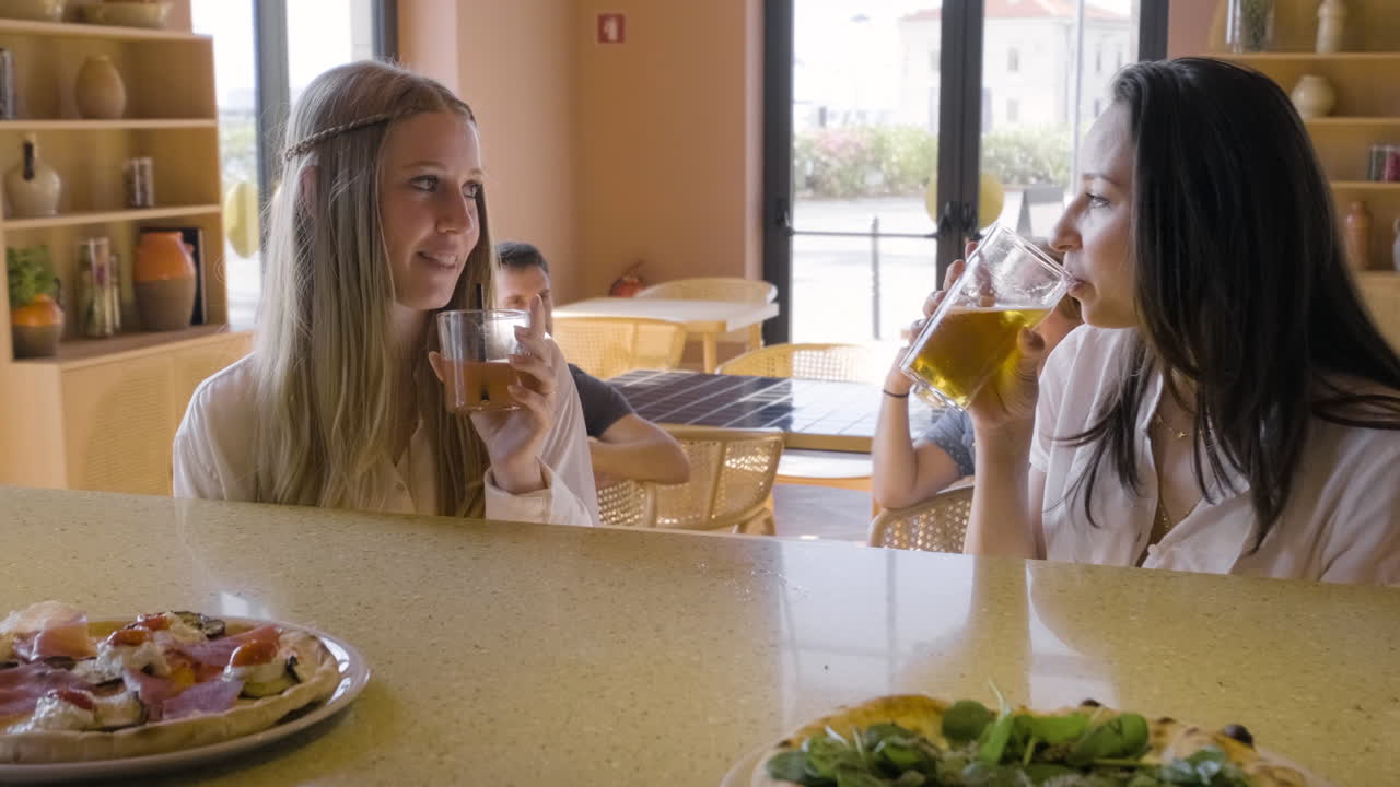 레스토랑 바에 앉아 술을 마시고 이야기하는 여성들의 정면도