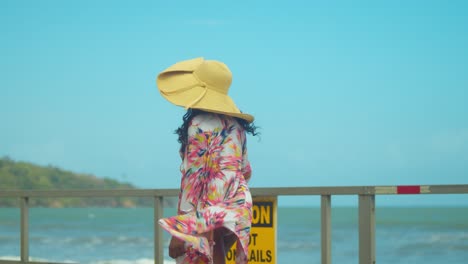 sexy girl walks on a boardwalk in a bikini with mountains and ocean waves crashing in the background