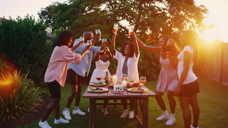 happy friends toasting at an outdoor garden party during golden hour