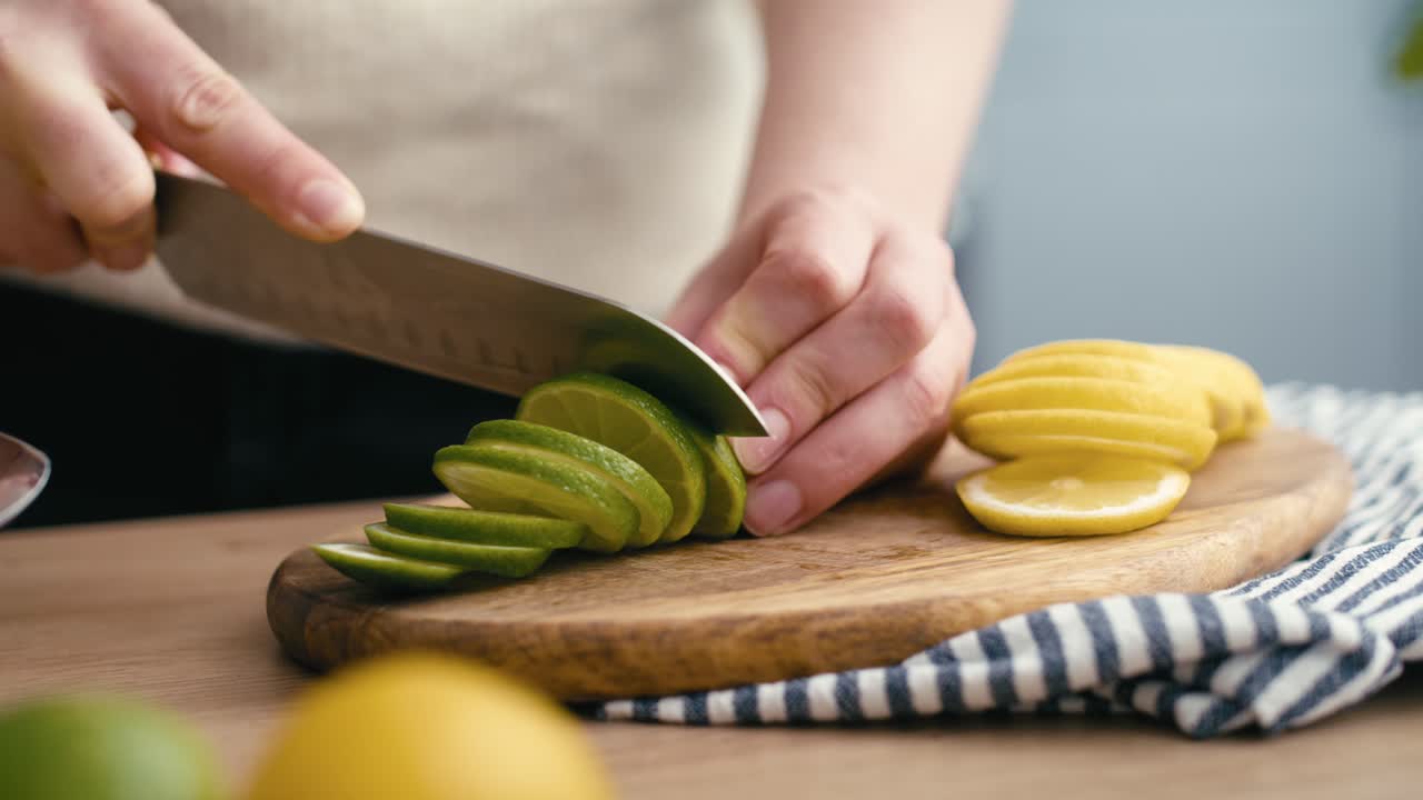 primer plano de una mujer cortando cal en la cocina.