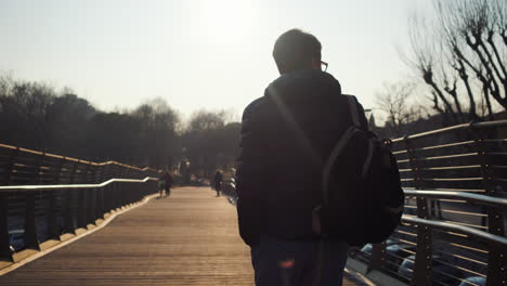 man die op een brug in een stad loopt