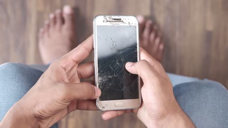 person holding a phone with a cracked screen