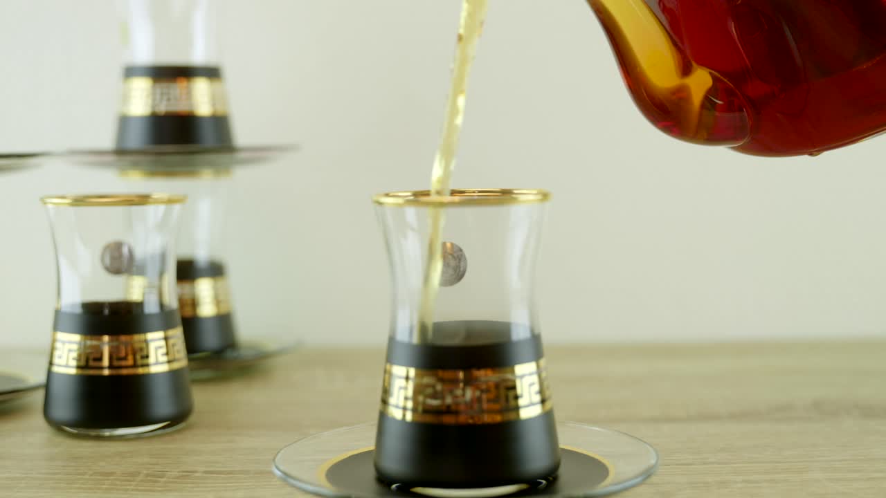 This mesmerizing stock footage captures the enchanting ritual of pouring fragrant Turkish tea from a transparent teapot into a traditional Turkish tea glass