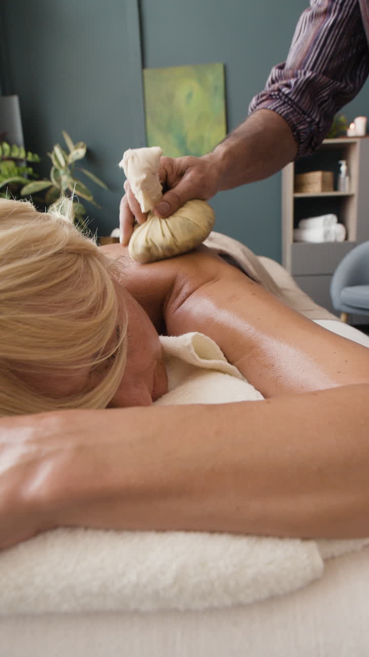 Woman receiving a relaxing herbal compress massage