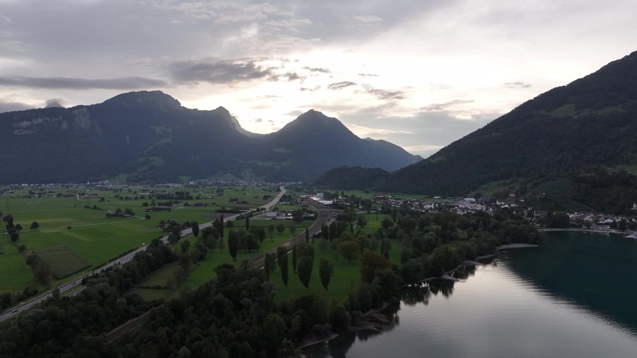 Rauhallinen ilmakuva Walensee-järvestä lähellä Wesseniä, Glarus Nordia, Sveitsiä, esittäen pienen venesataman ja viehättävän asuinalueen rauhallisilla rannoilla ja vuoristomaiseman.