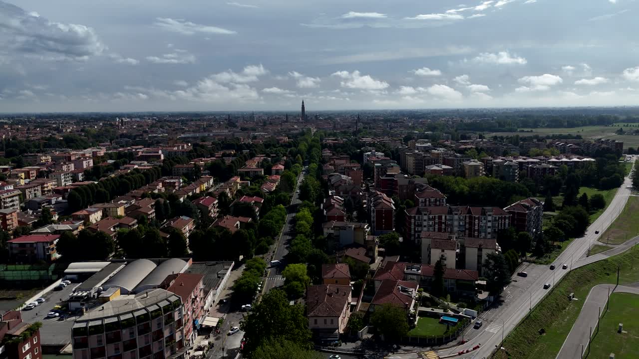 Drone aerial view of Cremona, Italy, showcasing the city’s layout with a central Po avenue leading to the iconic Torrazzo bell tower and Cathedral in Piazza Duomo, surrounded by green park
