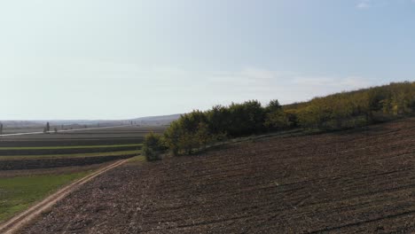 Aerial-view-over-farmlands-and-fields,-sunny,-autumn-day---rising,-drone-shot