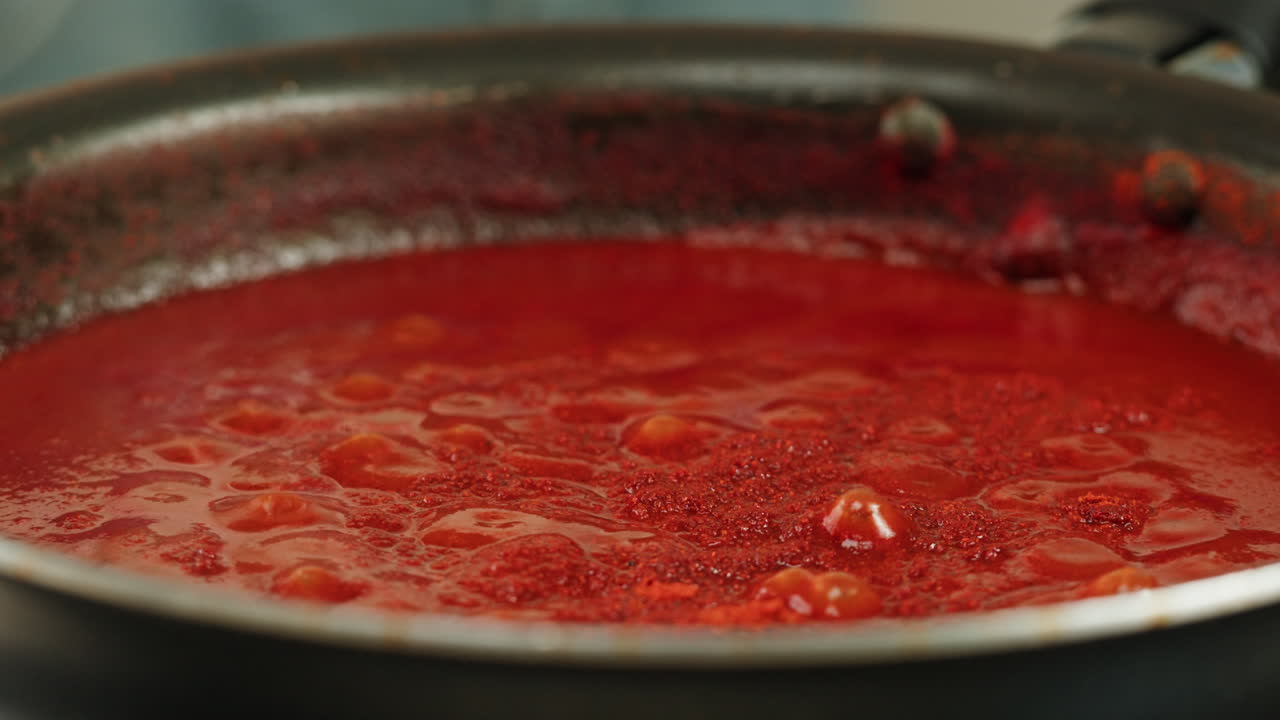 Chicken in tomato sauce is boiling on a frying pan with spices. Cooking tomato sauce curry with chicken fillet. Traditional Italian Mexican Asian dish. High quality studio shot for cafe, restaurant close up.