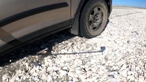 Low-angle-action-cam-POV-of-SUV-overlanding-rocky-beach-road