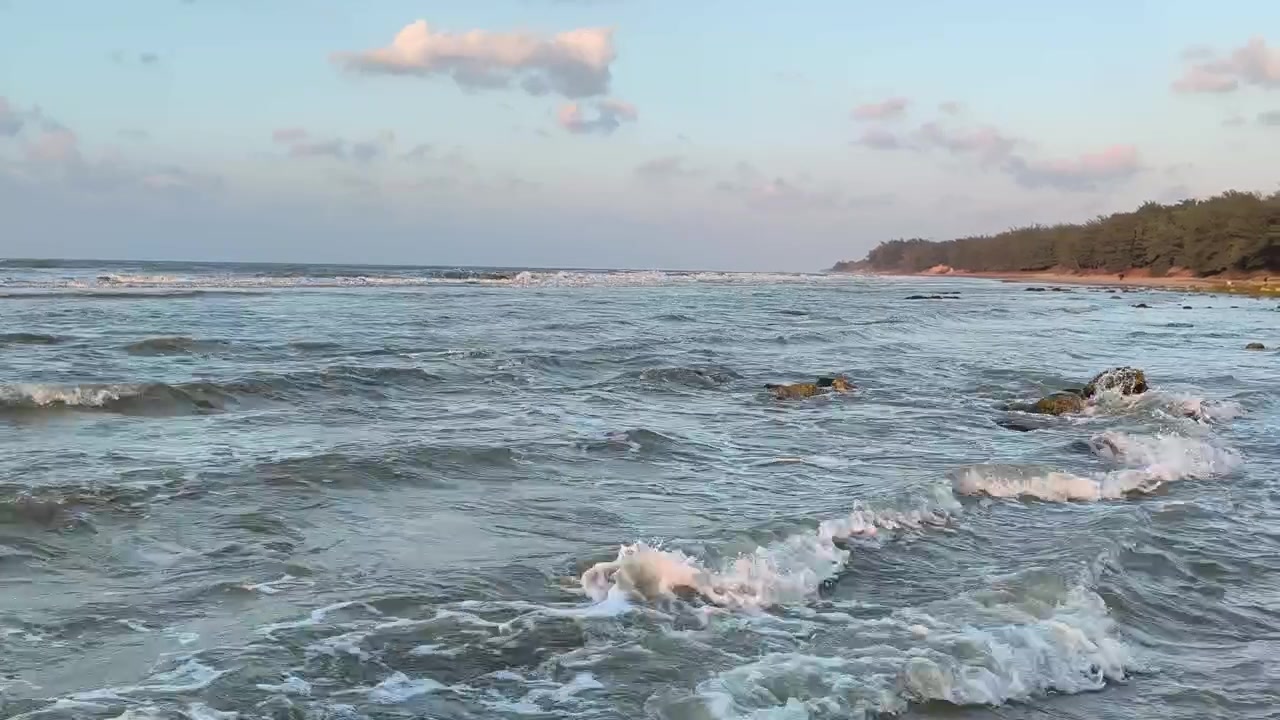 Onde leggere che si infrangono su una spiaggia rocciosa al tramonto