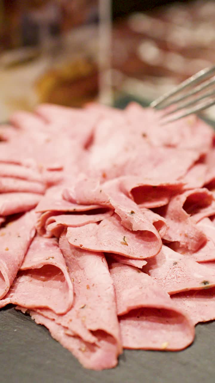 Una forchetta prende sottili fette di roast beef da un vassoio a un buffet.