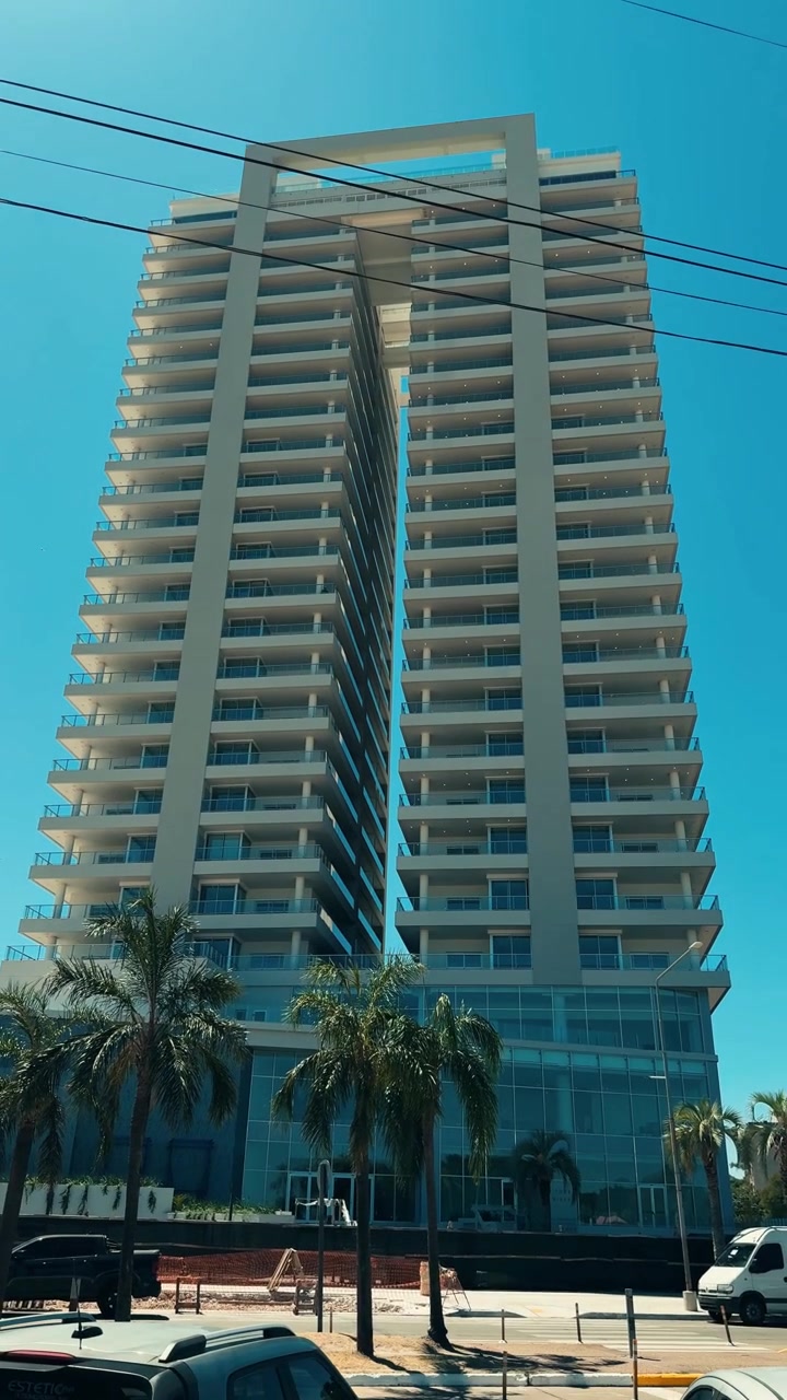 Edificio moderno de gran altura con balcones bajo un cielo azul despejado