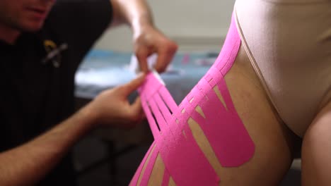 applying kinesiology tape to thigh