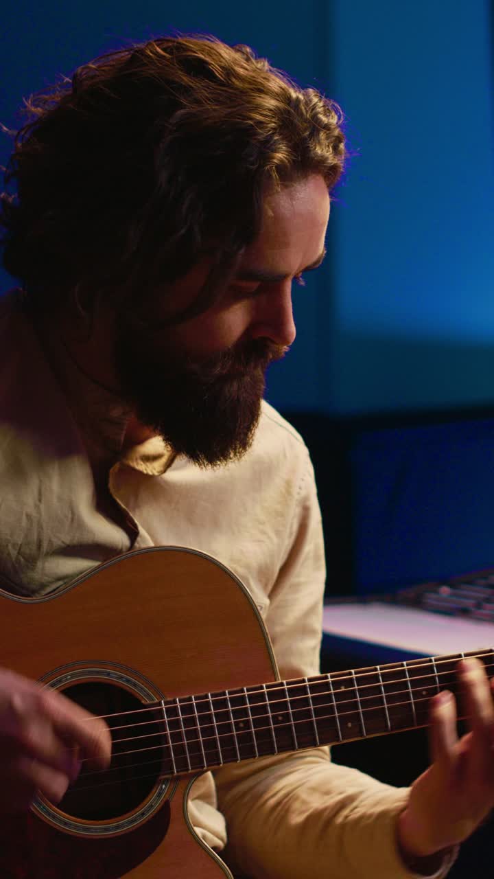 Hombre barbudo tocando la guitarra acústica en un estudio