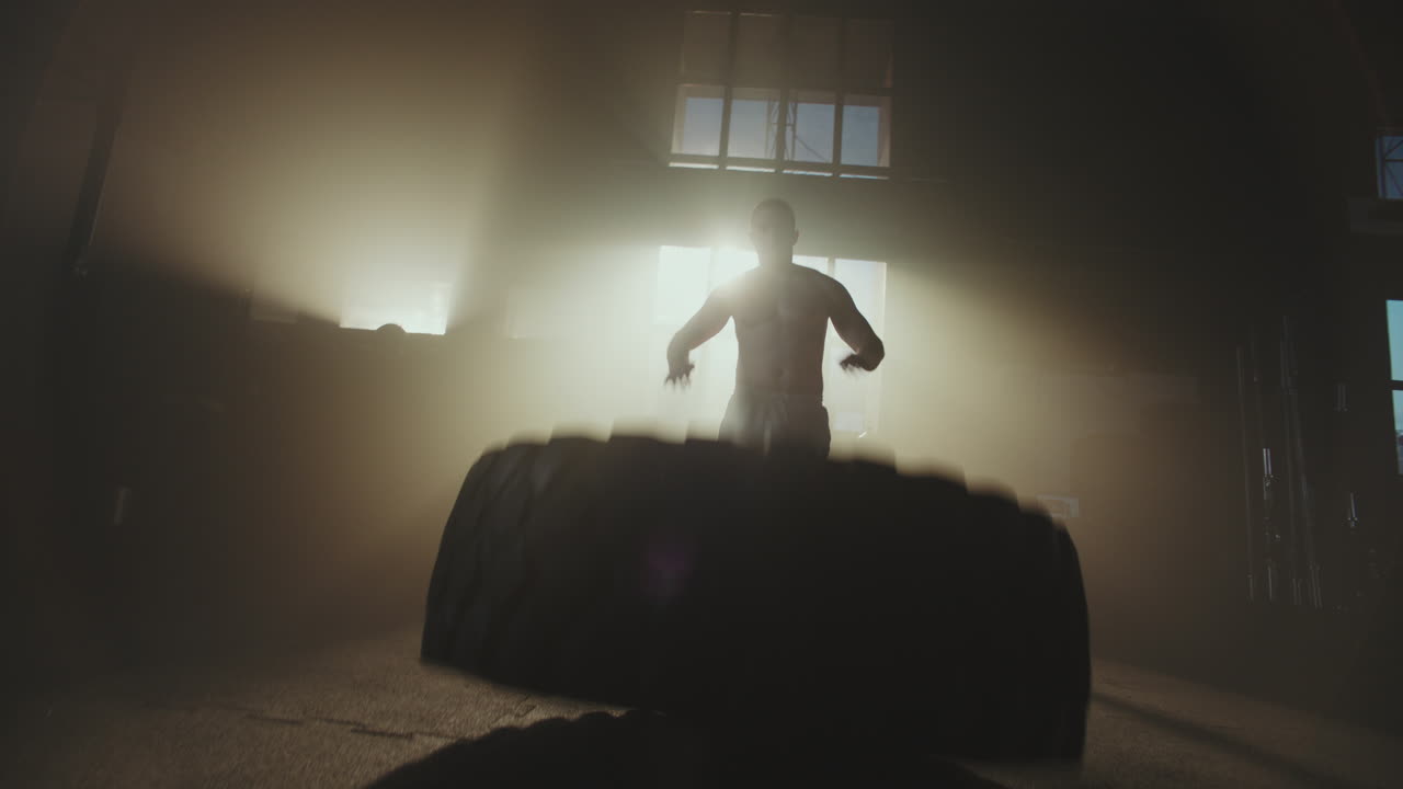 Man Performing Tire Flip Exercise in a Gym