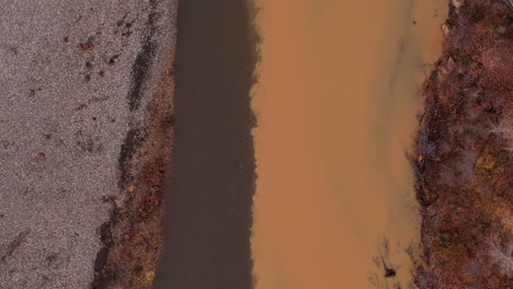 ogilvie river with muddy water flowing in yukon territory, canada. aerial topdown shot
