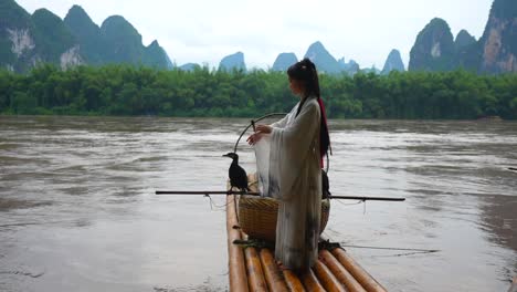 hanfu girl posing on bamboo raft with cormorant on li river