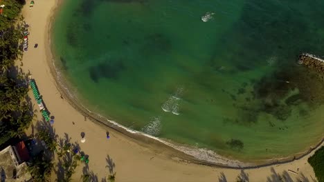 Miami-beach-with-clear-turquoise-waters-and-sunbathers,-vibrant-umbrellas-dot-the-sands,-aerial-view,-America