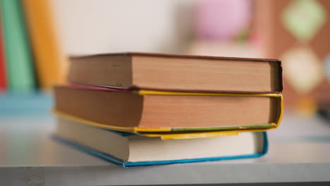 Little-girl-puts-textbooks-on-desk-with-supplies-at-home