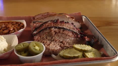 Tray-of-traditional-Texas-style-moist-smoked-brisket-and-sliced-turkey-plated-with-pinto-beans-potato-salad,-slider-close-up-4K