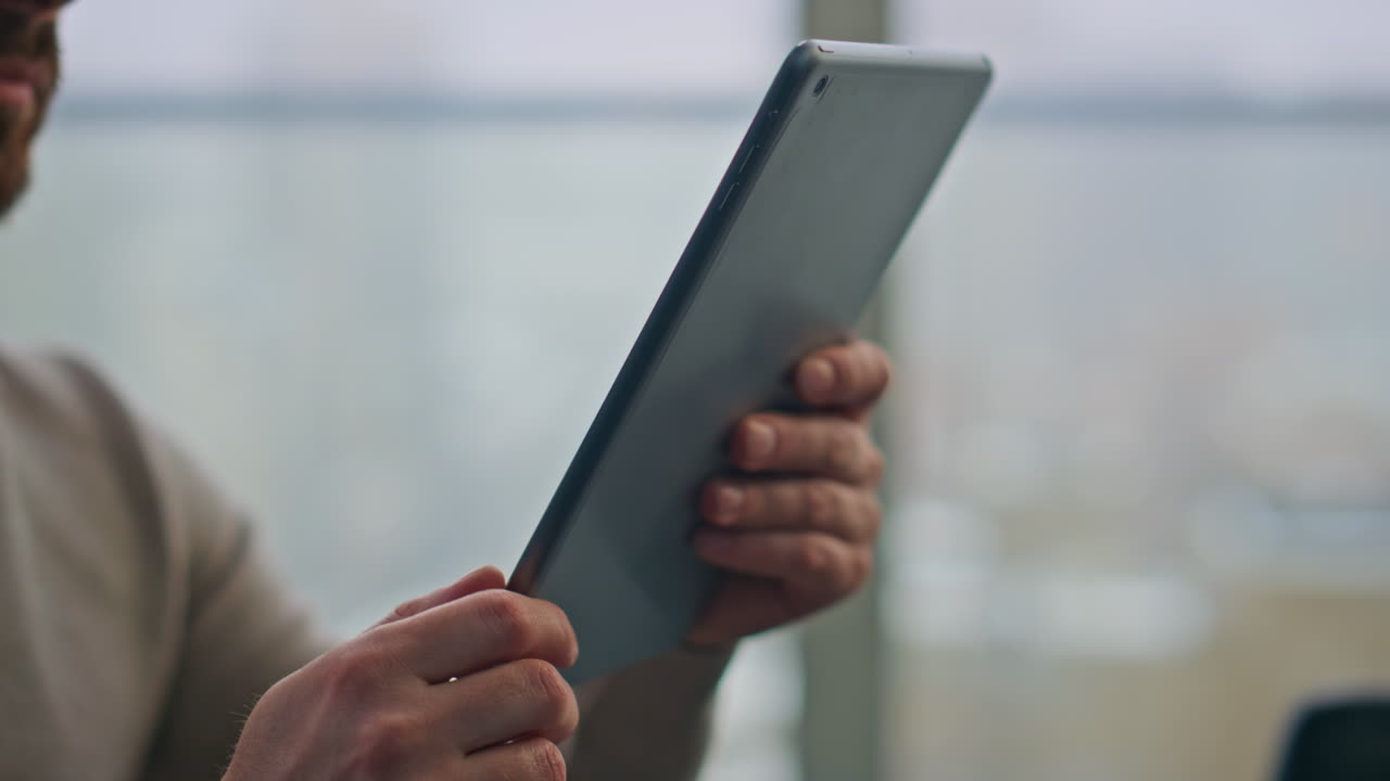 남자 손으로 문자 메시지를 보내는 태블릿 파노라마 아파트 클로즈업.