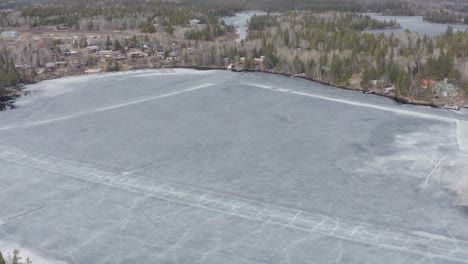 Círculo-Aéreo-Dejado-Sobre-El-Lago-Congelado-Derritiéndose-Con-Grietas-En-Los-Caminos-De-Hielo-Aún-Visibles-En-Canadá