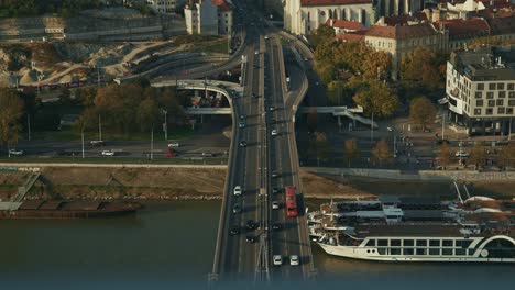 bratislava bridge with cars, red trams, and riverboats on the danube in warm light