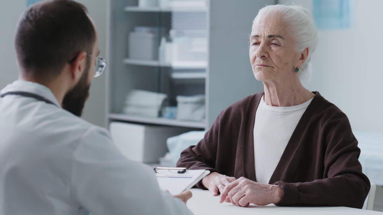 Elderly Woman Talking and Listening to Physician during Medical Consultation