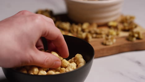 close up of hand choosing from bowl of hazelnut nuts in studio