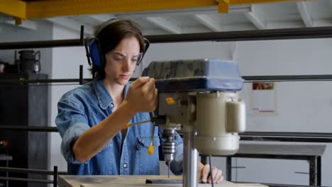 female welder using drill press machine in workshop 4k