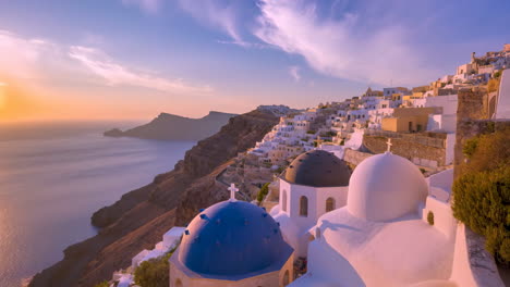 vibrant sunset over oia village and blue domes in santorini, greece