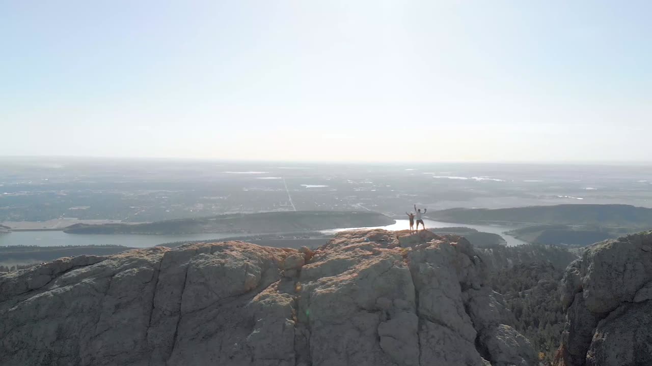 Drone shot of mountainous terrain, hikers  and cityscape in the distance. The shots also feature aerial shots of lakes in the distance as well as flybys and other interesting features.