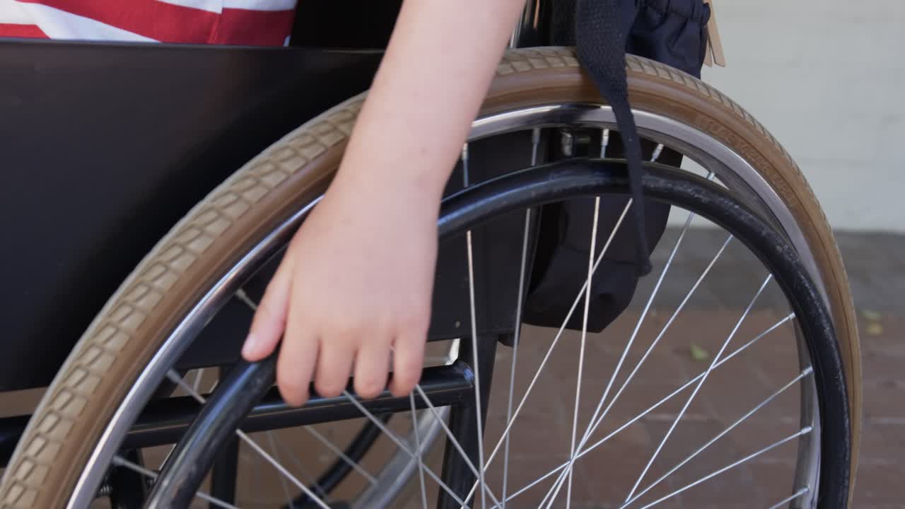 Right hand and forearm are touching handrim, sliding and pushing to propel wheelchair on pavement