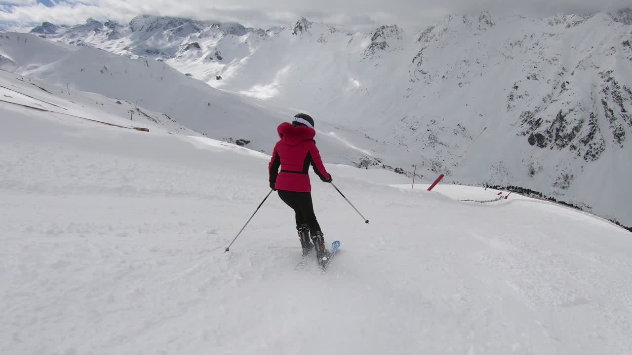 Donna che scia lungo le piste con ottima tecnica sciistica e a ritmo perfetto.
