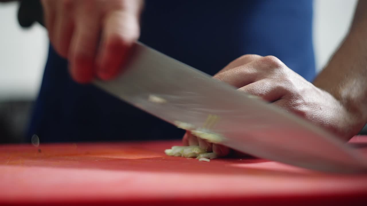 Close up view of a chef quickly cutting celery sticks in julienne over a board.