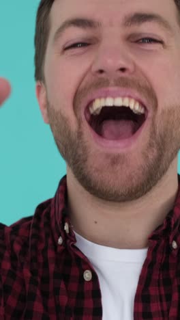 bearded man is the winner rejoicing showing victory gesture on blue background in studio bearded man is the winner rejoicing showing victory gesture on blue background in studio a happy man expresses success