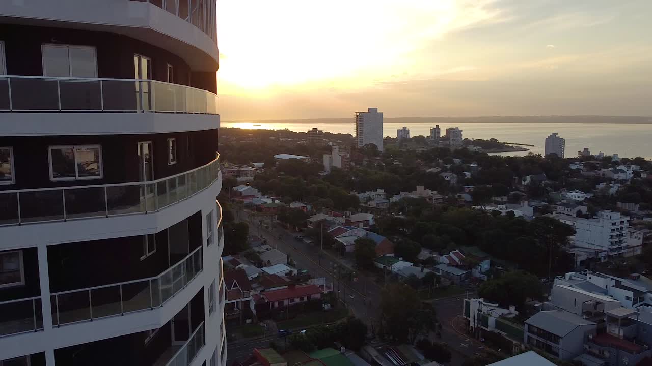 Filmagens aéreas de drone de um edifício de apartamentos de grande altura com vista para a cidade ao pôr do sol