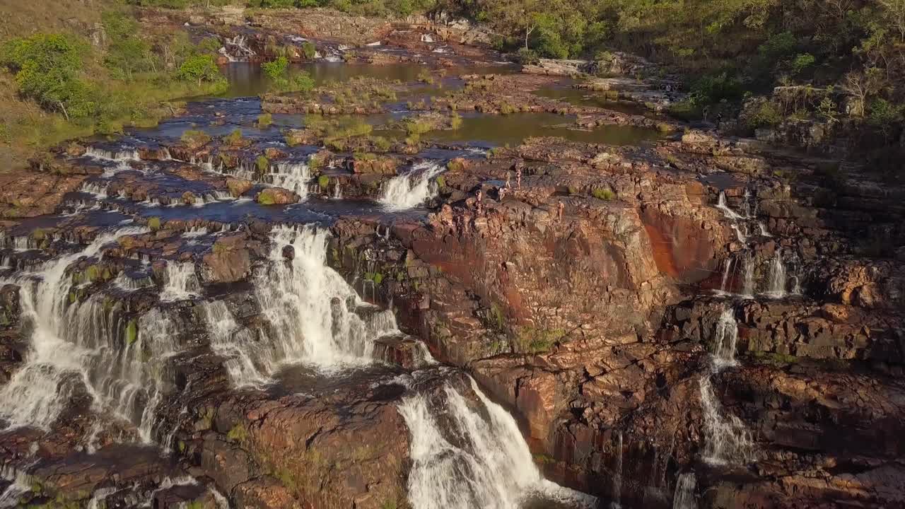Cinematic drone shot flying forward and tilting down, capturing a massive waterfall during sunset in Chapada dos Veadeiros, Goiás, Brazil
